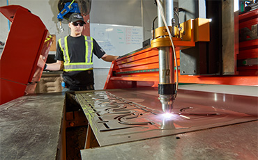 AF1 employee operating laser cutter to produce parts for custom air knife systems